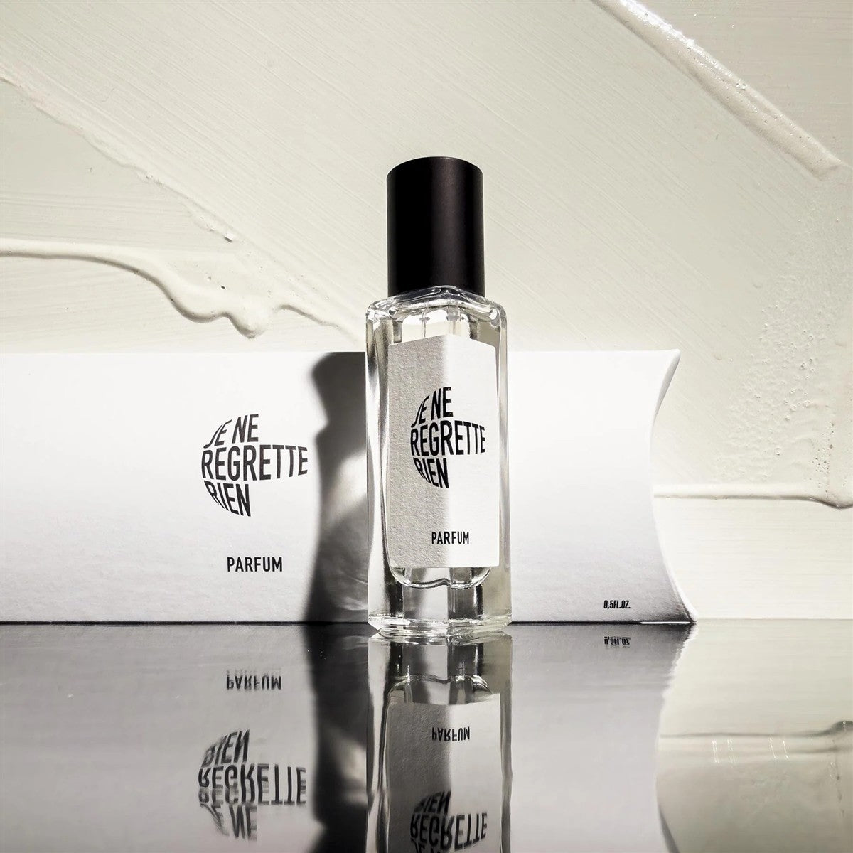 Je Ne Regrette Rien Parfum – klares Glasfläschchen 15ml, schwarzer Verschluss, weißer Hintergrund – Parfüm