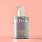 NEOM Real Luxury Hand Wash – durchsichtige Flasche 300ml, weißer Pumpverschluss, rosafarbener Hintergrund – Handpflege