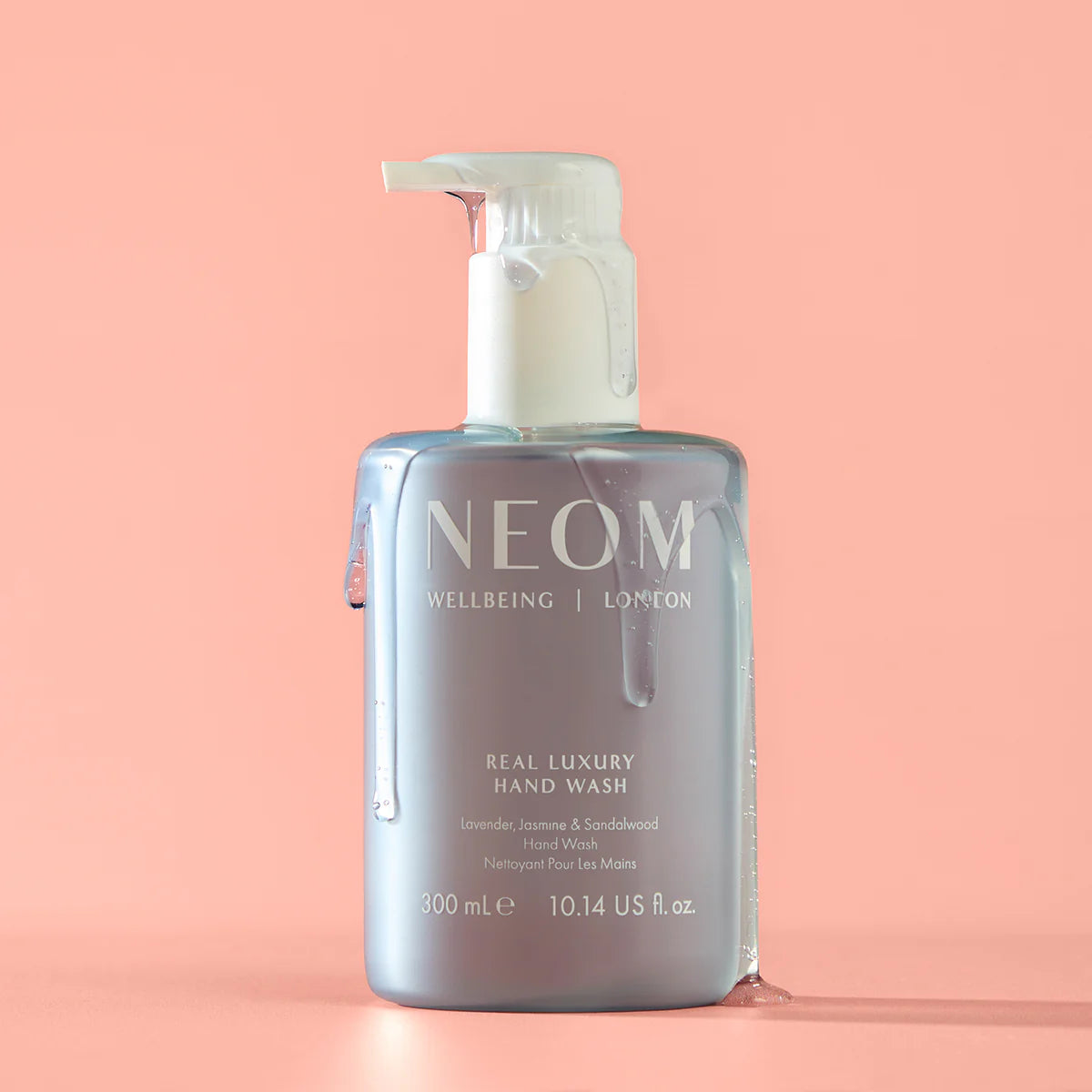 NEOM Real Luxury Hand Wash – durchsichtige Flasche 300ml, weißer Pumpverschluss, rosafarbener Hintergrund – Handpflege