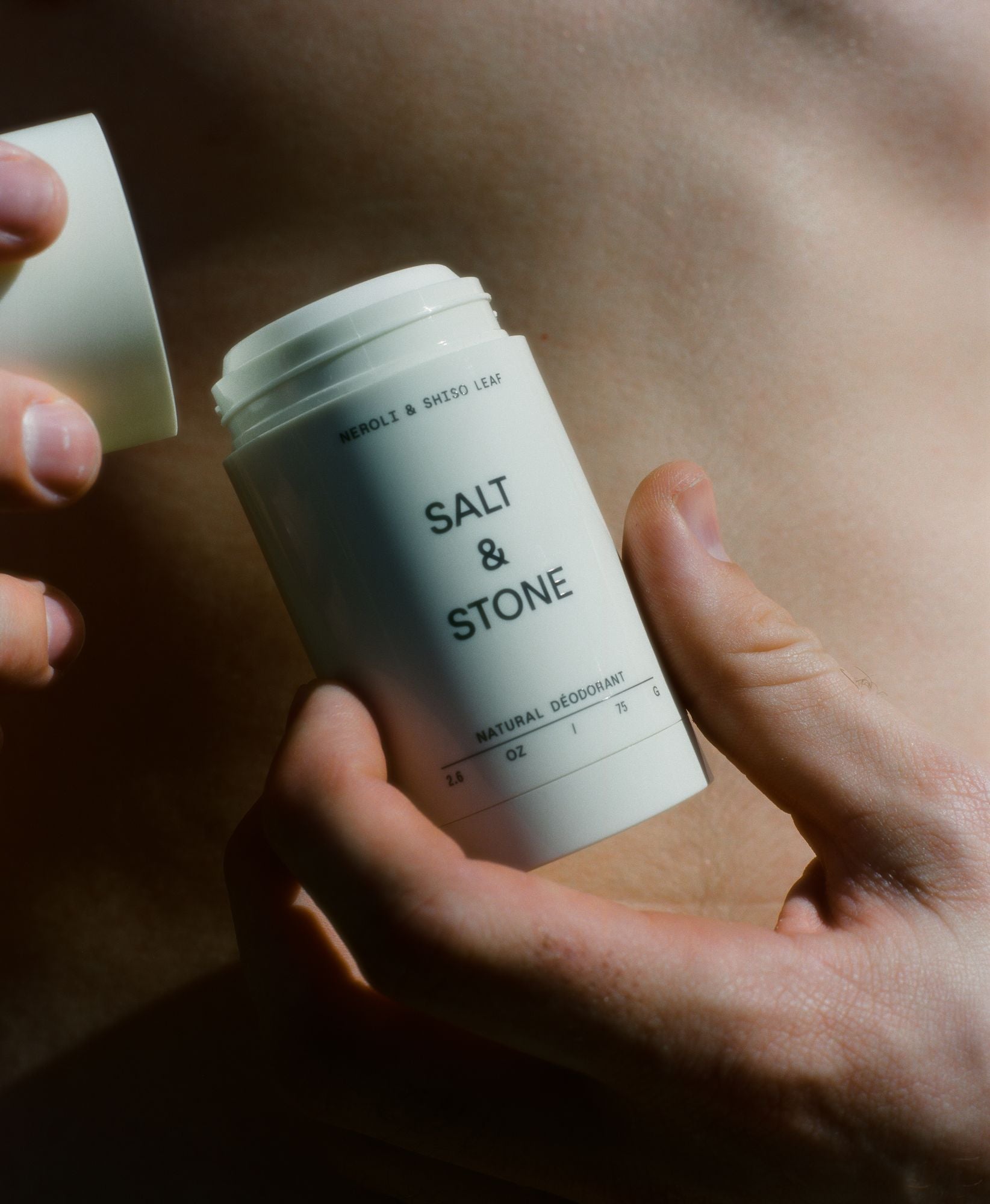 Salt & Stone Neroli & Basil Deo Extra Strength – weißer Stift 75g, abgenommener Deckel, Haut-Hintergrund – natürliche Körperpflege