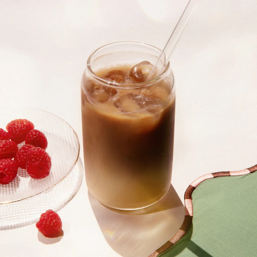 Herbal Koffee – Glas mit Eiswürfeln und Strohhalm, weißer Hintergrund, Himbeeren daneben – Getränk