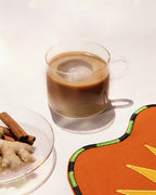 Chai Koffee – clear mug with brown drink, ice cube, cinnamon sticks and ginger in background – beverages