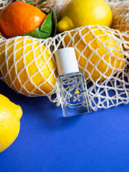 Esprit de Contradiction Eau de Parfum – clear glass bottle with white spray cap, blue background, citrus fruits – perfume