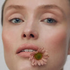 Cream Blush Precious Refill – Gesicht mit rosafarbenem Blush, Blume am Mund, neutraler Hintergrund – Make-up