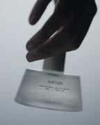 Nurture Eau de Parfum – 50ml glass bottle with spray nozzle, grey-white background – perfume