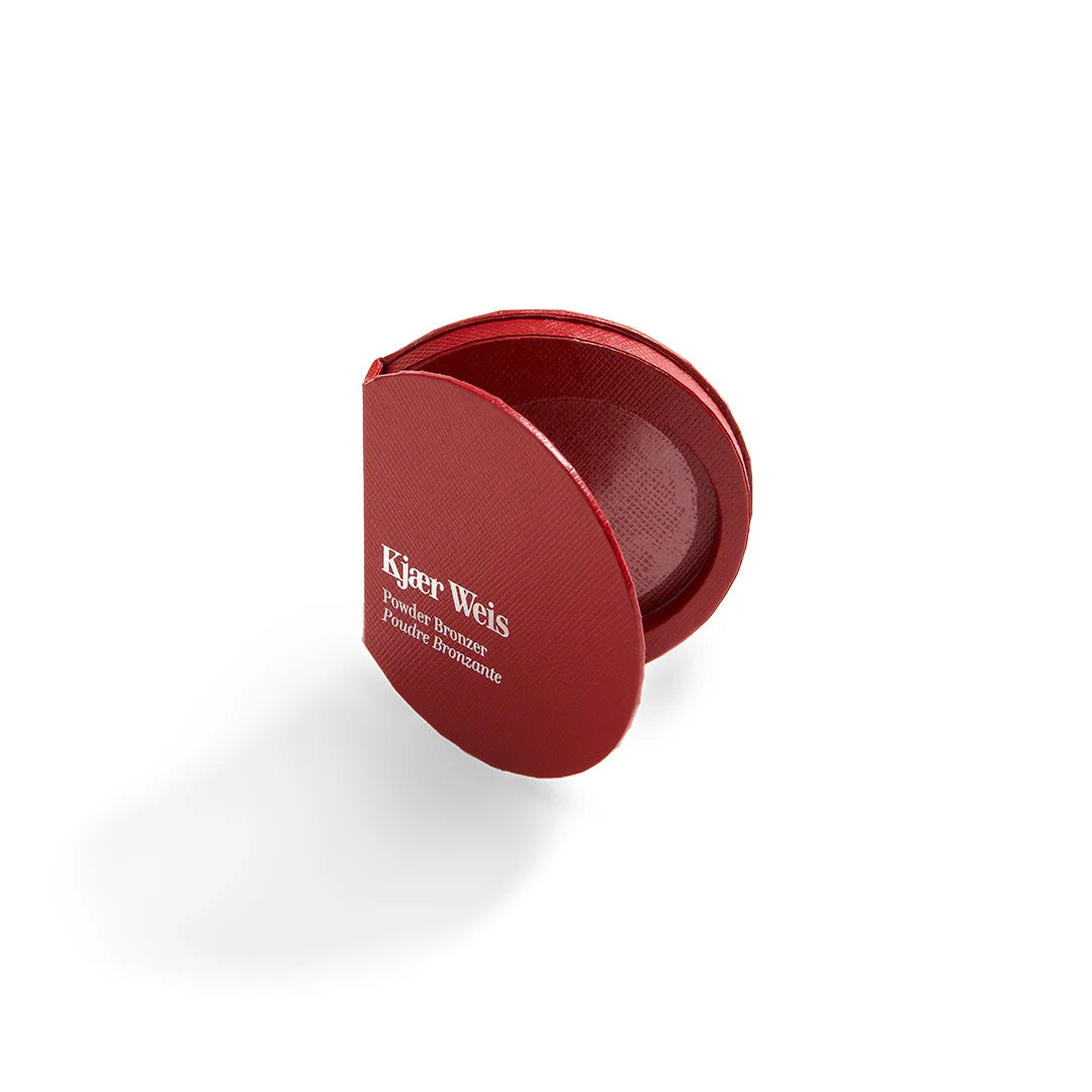 Kjaer Weis Powder Bronzer – roter Puderdose, geöffnet, weißer Hintergrund – Make-up