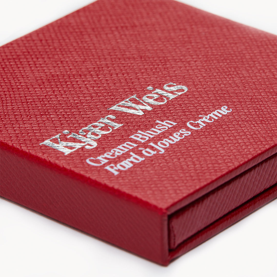 Kjaer Weis Cream Blush – rote Texturbox mit silberner Schrift, weißem Hintergrund – Gesichtsrouge