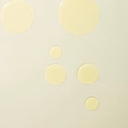 Holi(body) Ageless Body Sérum: Gelbe Serum-Tropfen auf hellem Hintergrund für die Hautpflege.