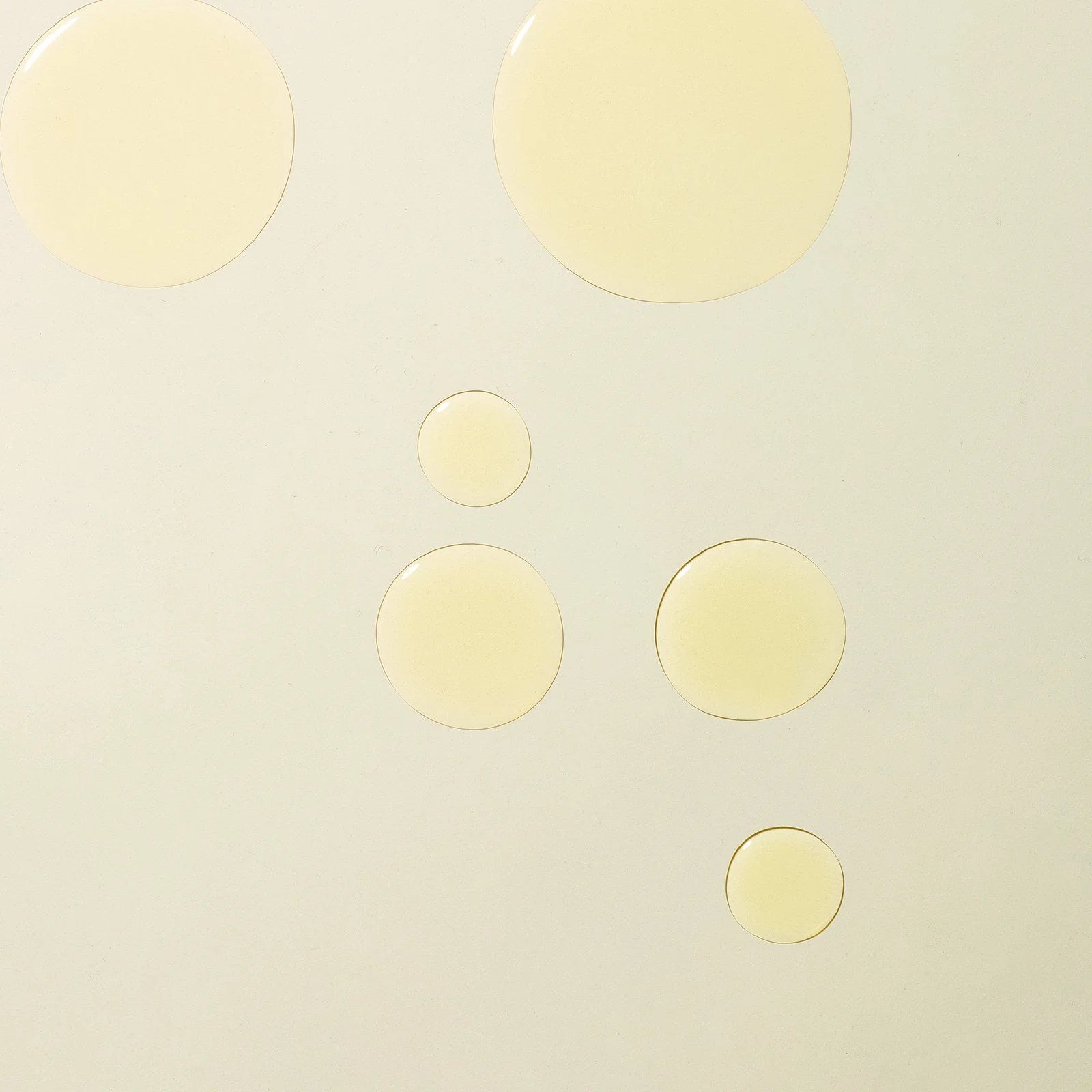 Holi(body) Ageless Body Sérum: Gelbe Serum-Tropfen auf hellem Hintergrund für die Hautpflege.