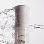 Weiße Flasche der holi (water) crème vor weißem Hintergrund mit Wasserspritzern, Hautpflege.