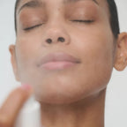 Frau nutzt SuperSerum Hydrating Mist Travel Spray für die Hautpflege auf weißem Hintergrund