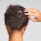 Metal French Hair Pin Silber in curly hair against a gray background, elegant hair accessory