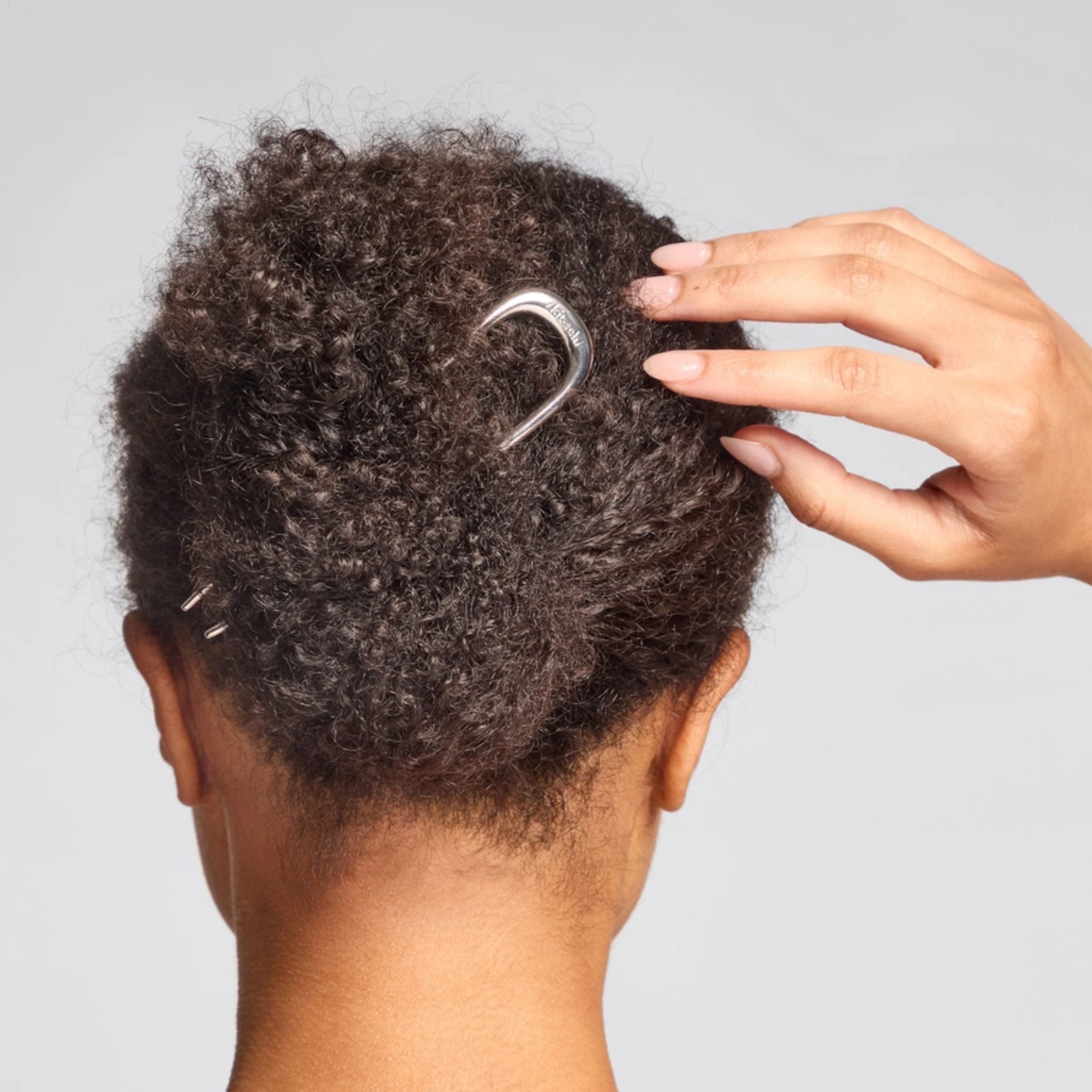 Metal French Hair Pin Silber in curly hair against a gray background, elegant hair accessory