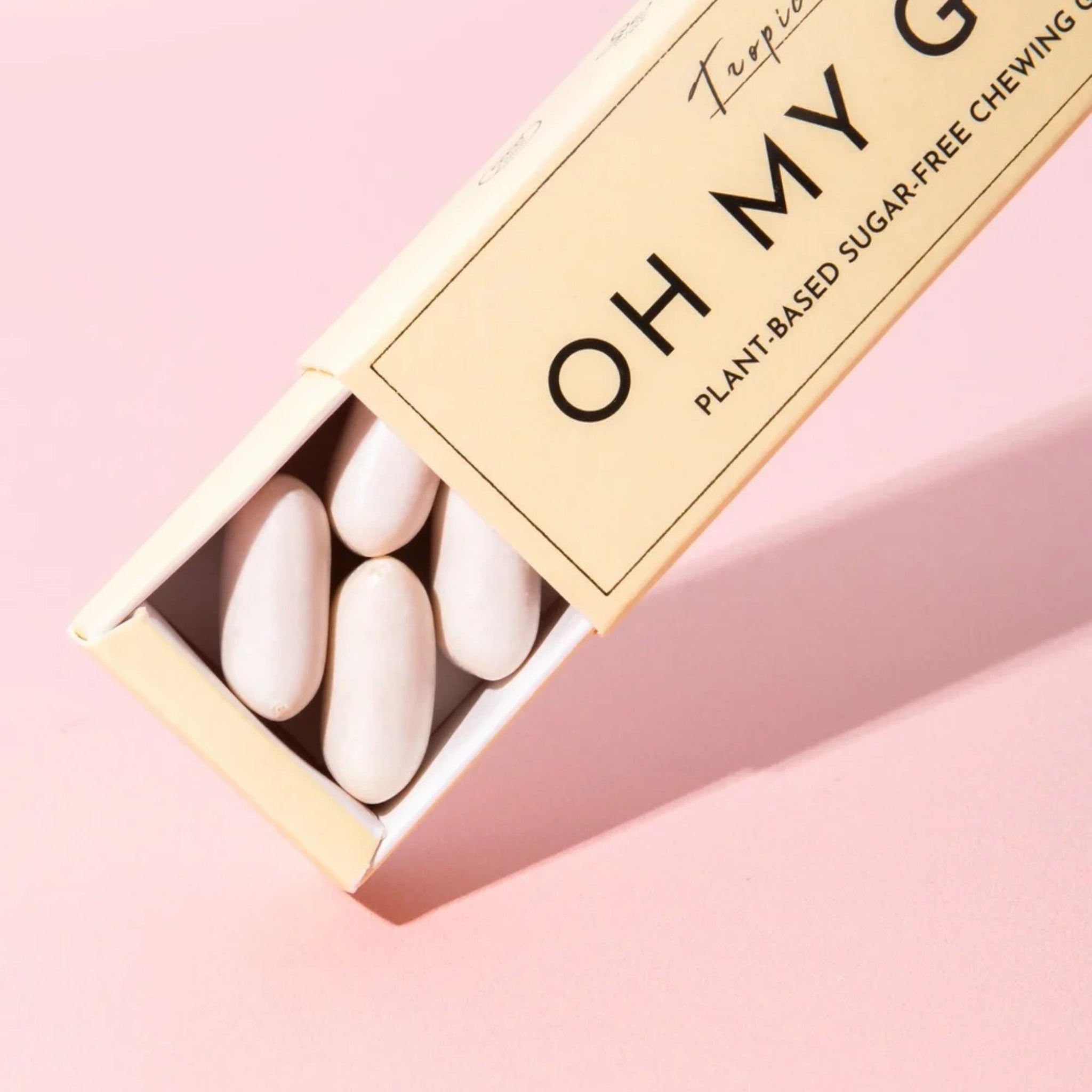 Oh My G Plant Based Chewing Gum Tropic in a beige cardboard box on a pink background, sugar-free chewing gum.