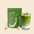 Cosmic Dealer Popcorn Matcha in grüner Packung vor beigem Hintergrund, organisches Matcha-Pulver.