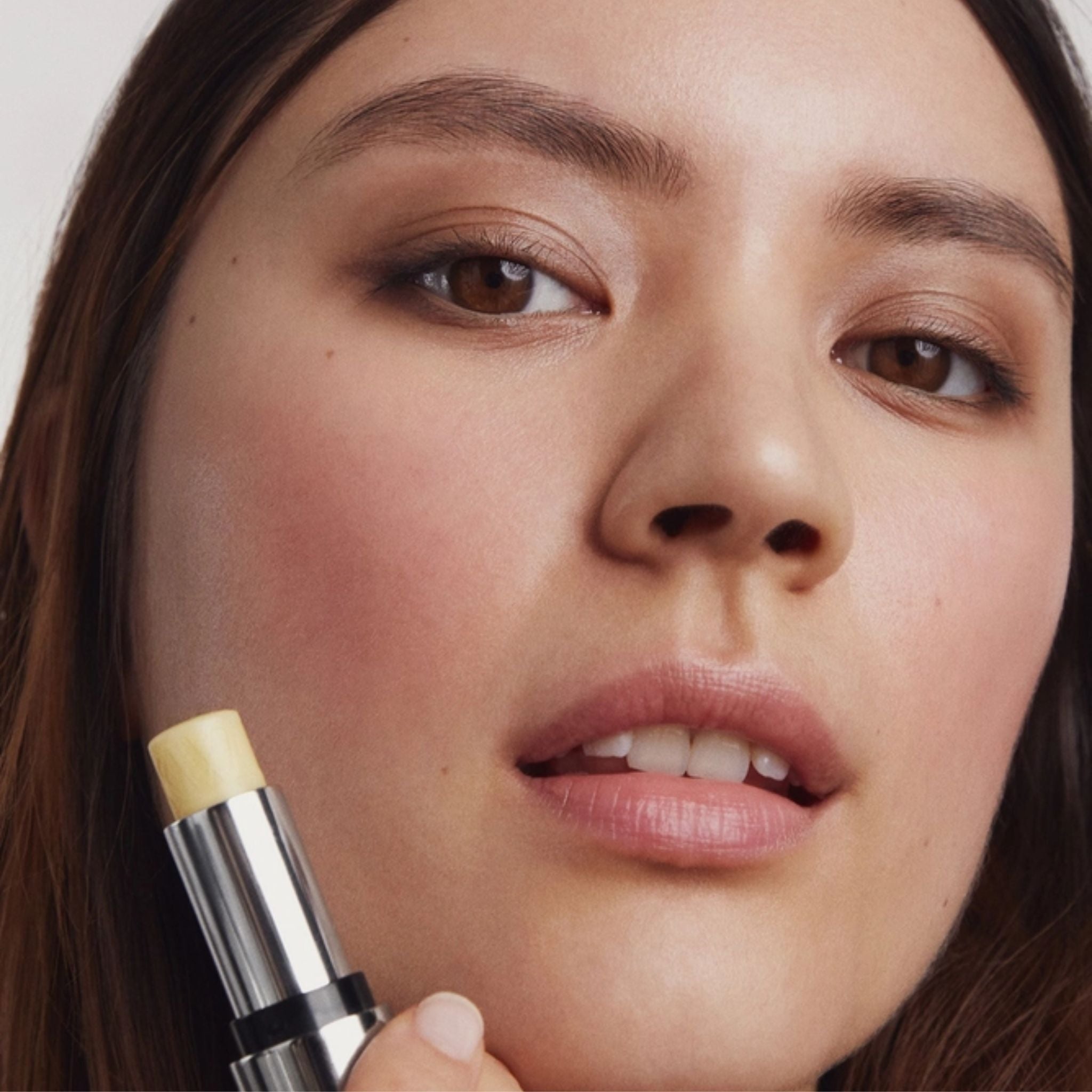 Tinted Lip Balm Clear in a silver tube with a model