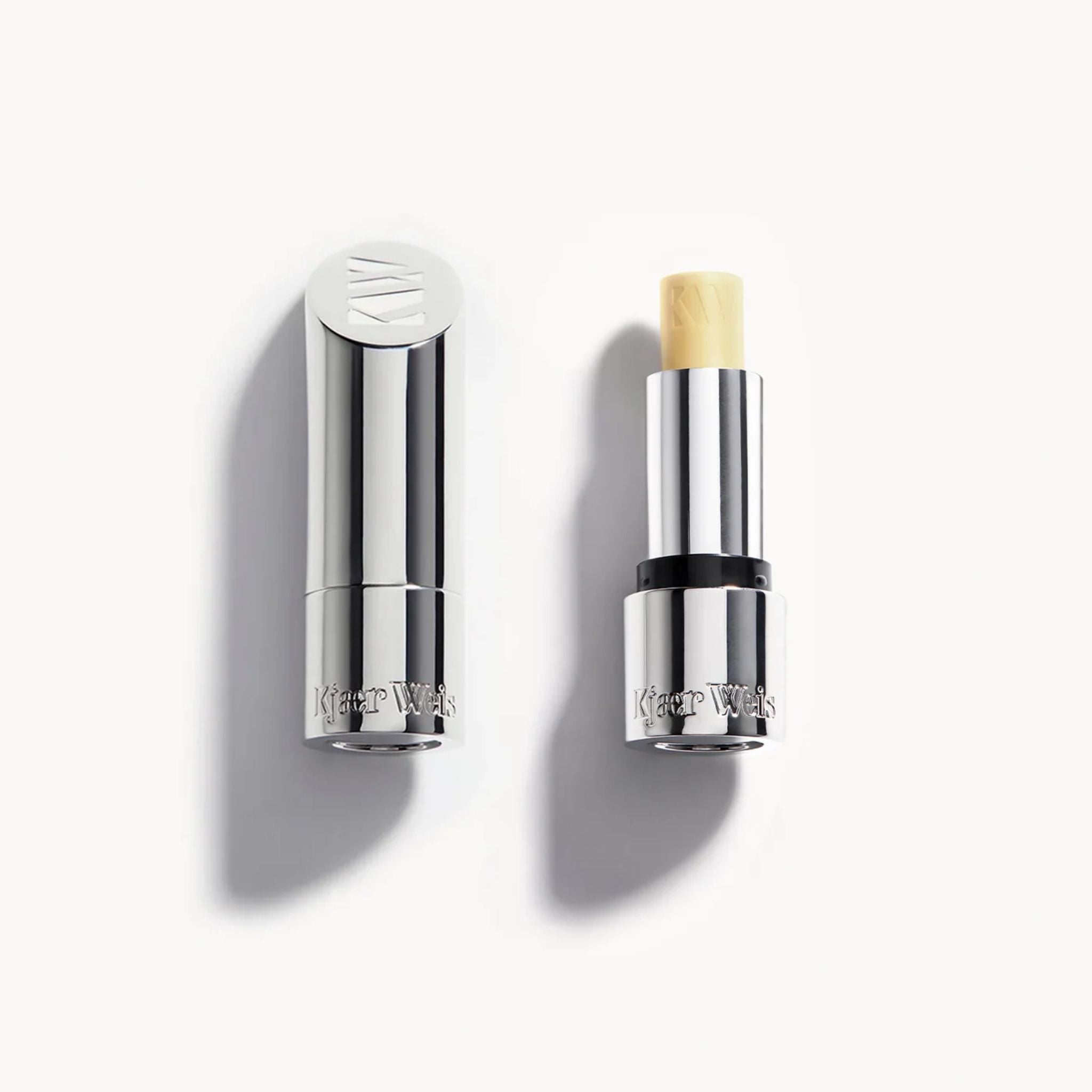Kjaer Weis Tinted Lip Balm Clear in a silver metal tube against a white background, lip care.