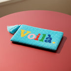 Voilà Clutch, light blue beaded clutch with colourful lettering on a reddish background.
